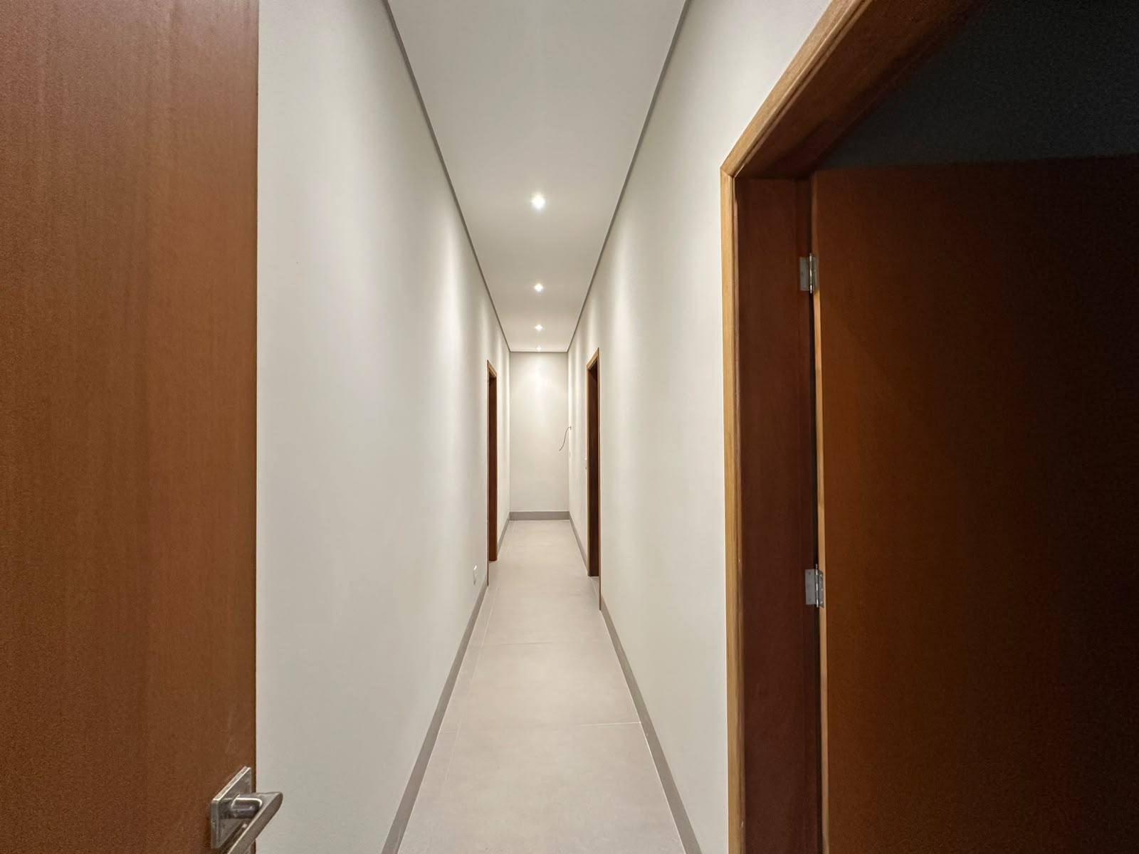 Corredor com iluminação embutida e portas em madeira