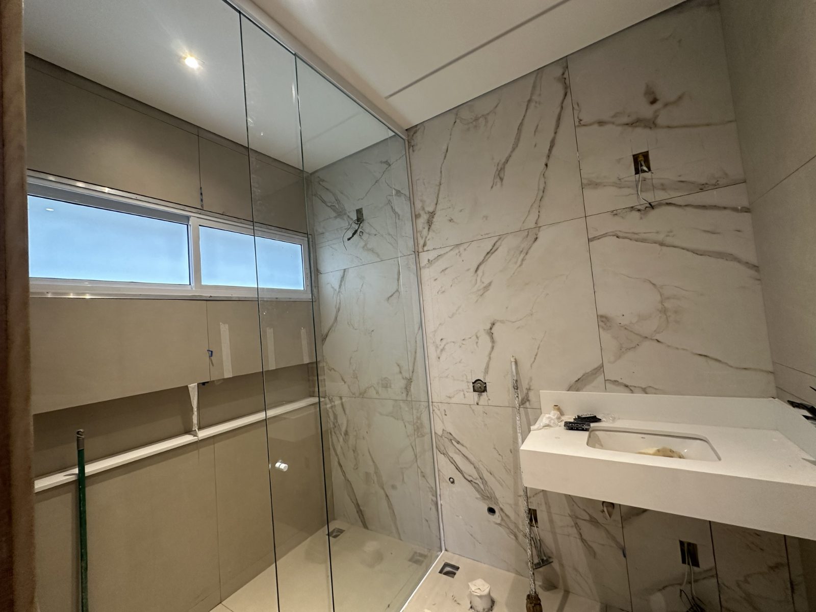 Banheiro com porcelanato marmorizado e box de vidro